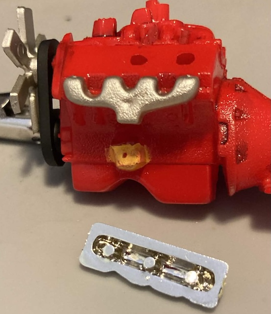 The chrome valve cover lying on the ground has 3 male studs and the block has just 2 female holes. Please ignore my terrible colouring of the oil filter.