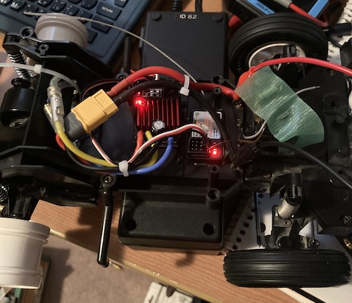 Two lights, one on the receiver, and one on the Quicrun ESC, are illuminated. Everything is stuck in a maze of poorly-made wiring.