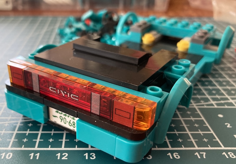 The rear bumper is being assembled, showing off the many custom curved pieces holding it together and the "CIVIC" tail light insert.