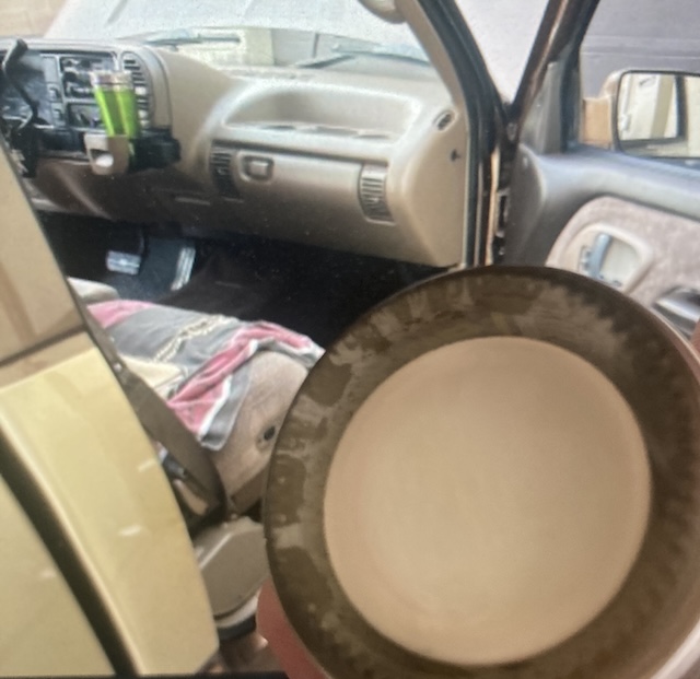 I am holding the bottom of a jar of tan liquid up to a picture on my computer screen showing the interior of a somewhat high mileage, much later model, GMT400.