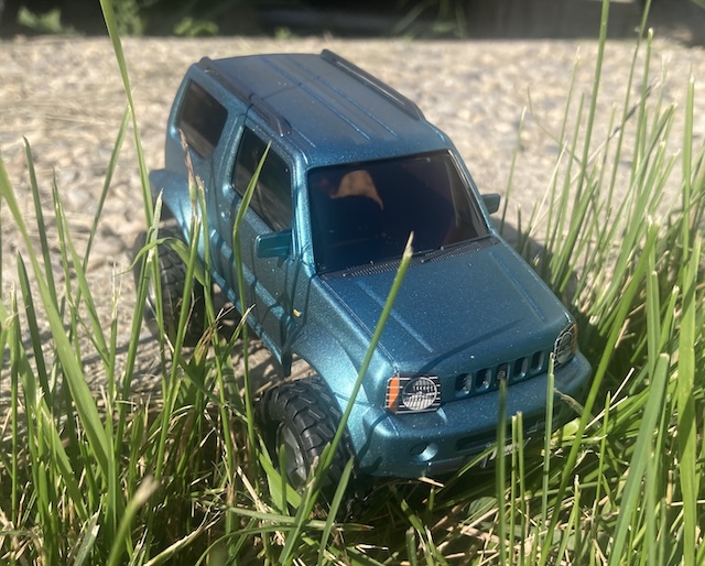 The Jimny is descending into the grass, ready for an adventure.