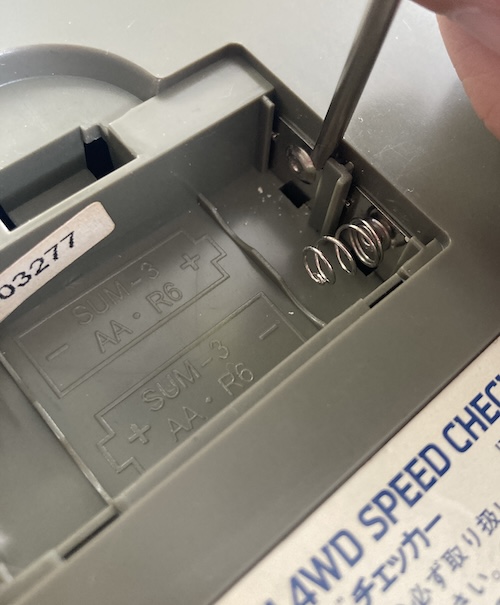 A Tamiya screwdriver is being used to remove some white corrosion from the battery terminals.