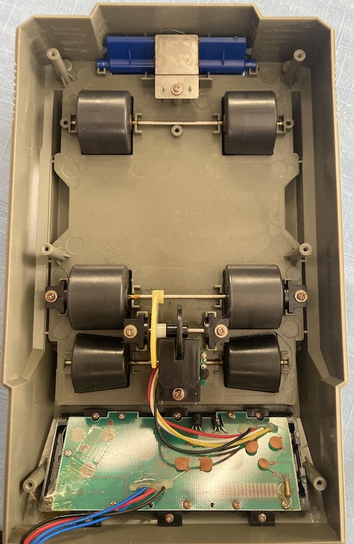 The Speed Checker's front wheel turns a shaft, which turns a small gear, which turns a big gear, which turns another shaft, which turns a wheel that spins inside a photosensor housing.