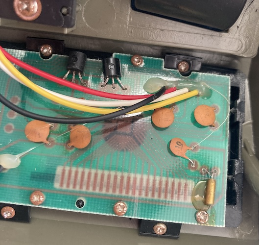 The microcontroller is stuck under a glob of black epoxy. Its connections lead to the zebra-connector for the LCD.