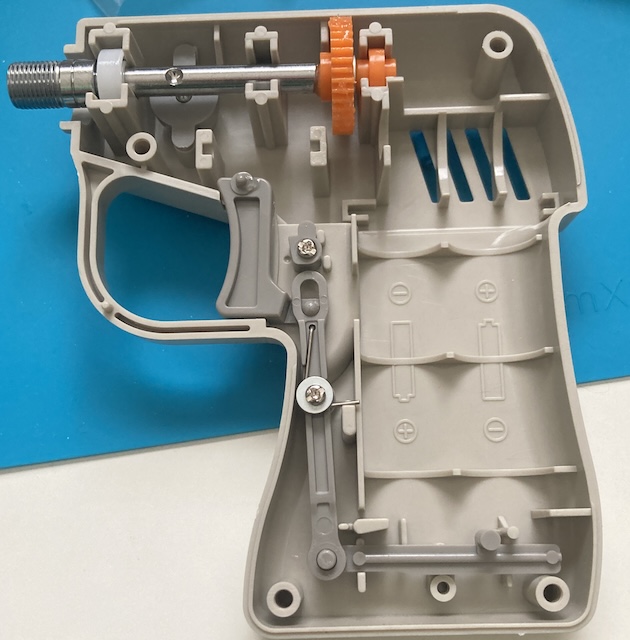 A long metallic shaft is installed into the business end of the router, with an orange drive gear and a white plastic 1150 bushing supporting it.